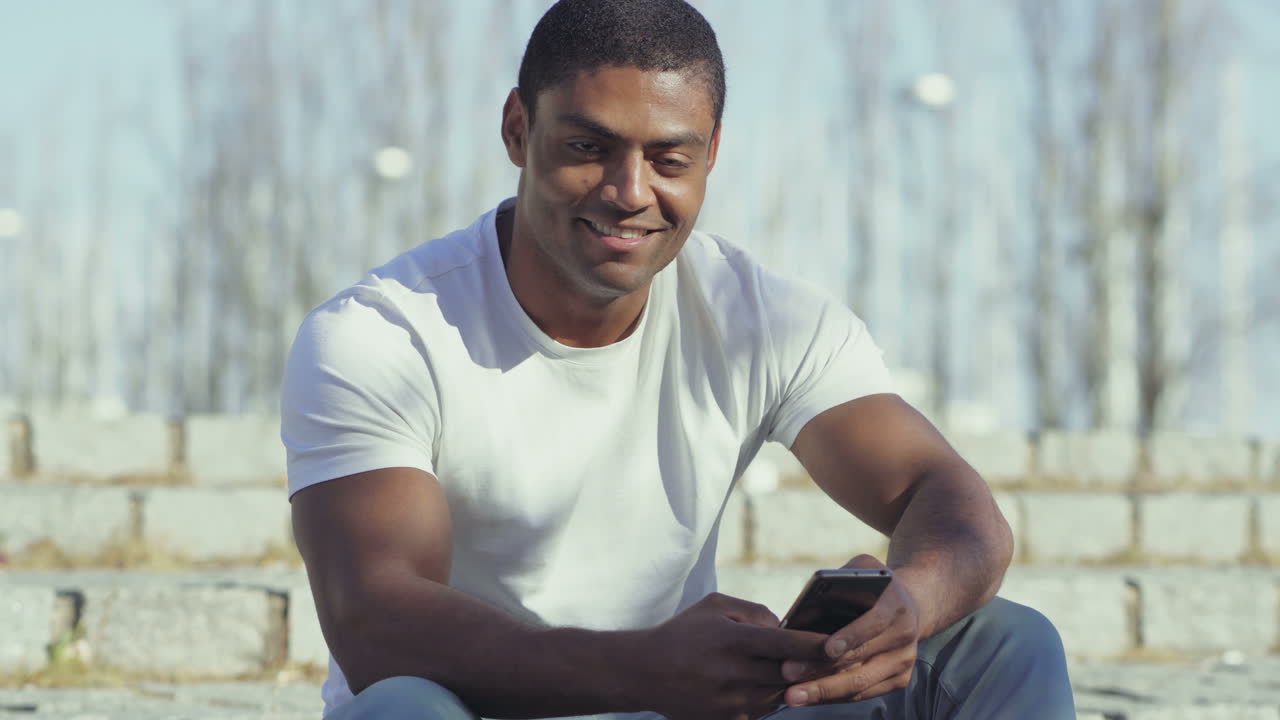 Smiling African American man holding smartphone.