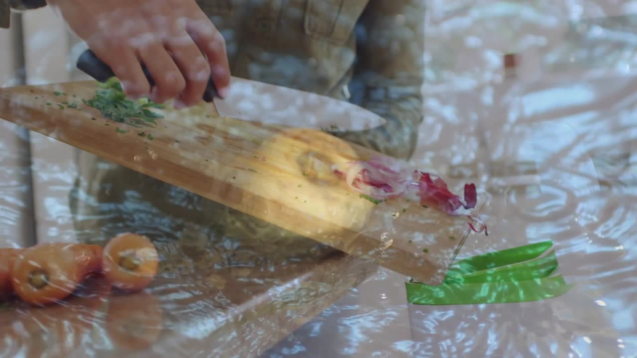 Woman gripping knife, slicing red onion, chopping herbs, tilting board for sliding into green tub