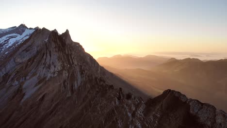 aerial flyover over schaefler in appenzell, switzerland with reverse motion revealing a person's silhouette against the sunset glow