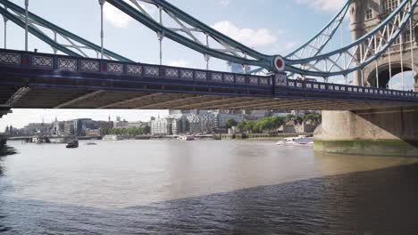 static view under side of tower bridge in london with few people and cars, cinematic shot