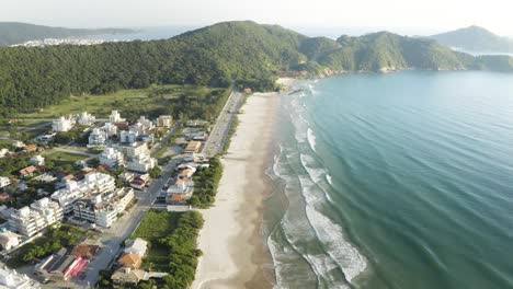 Vista-Aérea-Cinematográfica-Con-Un-Dron-De-Una-Playa-Con-Montañas-Selváticas-En-El-Horizonte-De-Una-Costa-Brasileña,-Mariscal,-Santa-Catarina,-Brasil