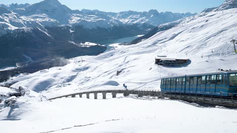 blue cable car going down surrounded by snowy winter landscape and mountains in st