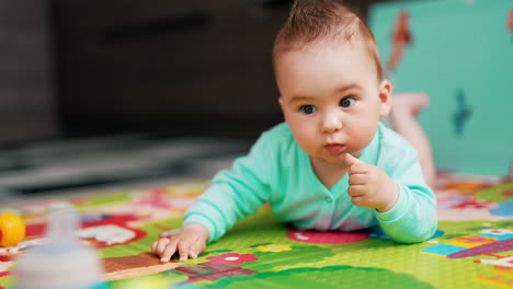 sweet baby boy with funny hair lies on a mat. adorable toddler interested with toys. close up.