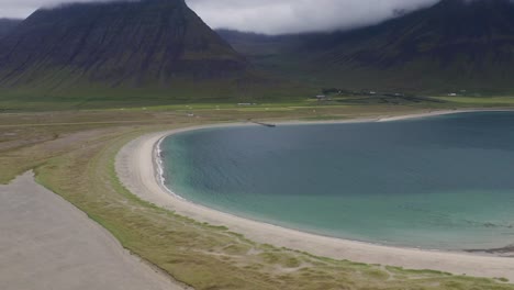 fotografía aérea de la playa de onundarfjordur con una gigantesca cordillera y el agua de la laguna azul en islandia