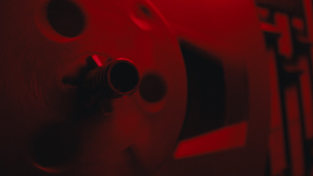A close-up on a vintage tape recorder in a red blinking light