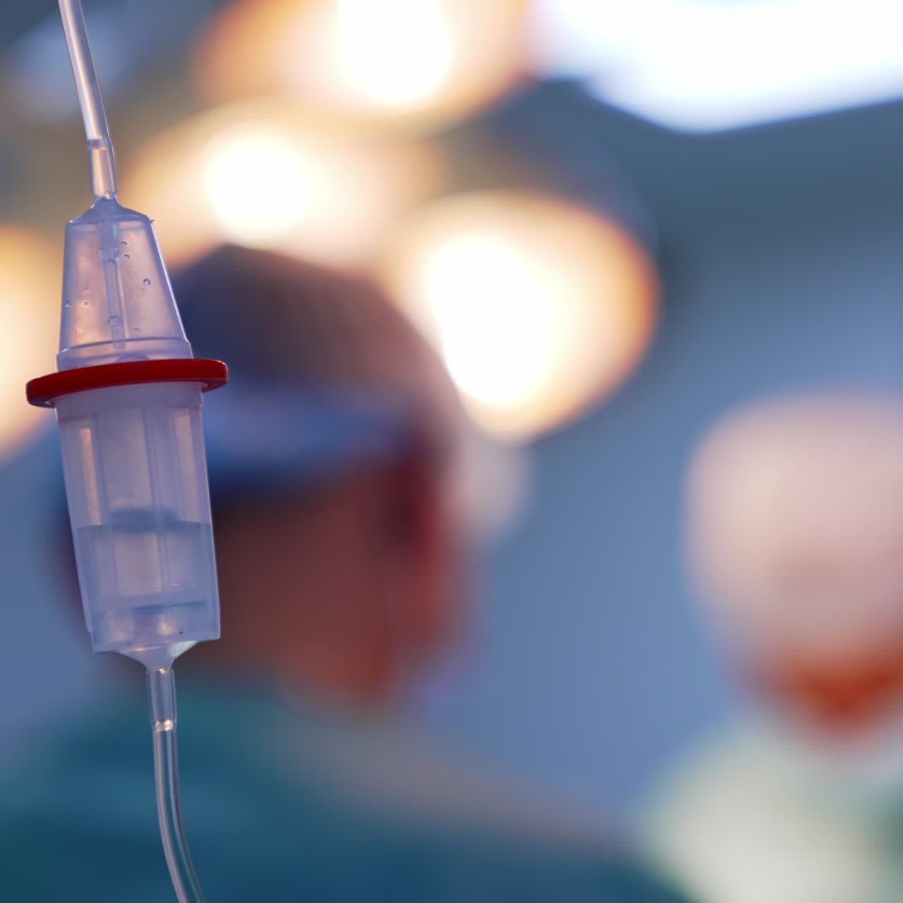 Quickly falling drops in the reservoir of plastic drop counter. Close up. Doctor in caps standing at backdrop in blur