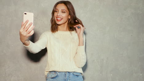 woman taking a selfie against a grey wall