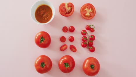 Video-of-fresh-red-tomatoes-and-tomato-sauce-with-copy-space-on-pink-background