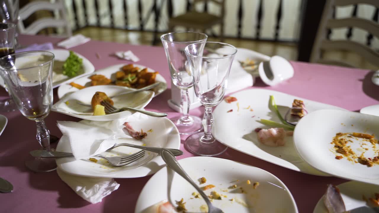 remnants of meat dishes and snacks are on the festive table after the feast. Camera motion to the right. Blurred background