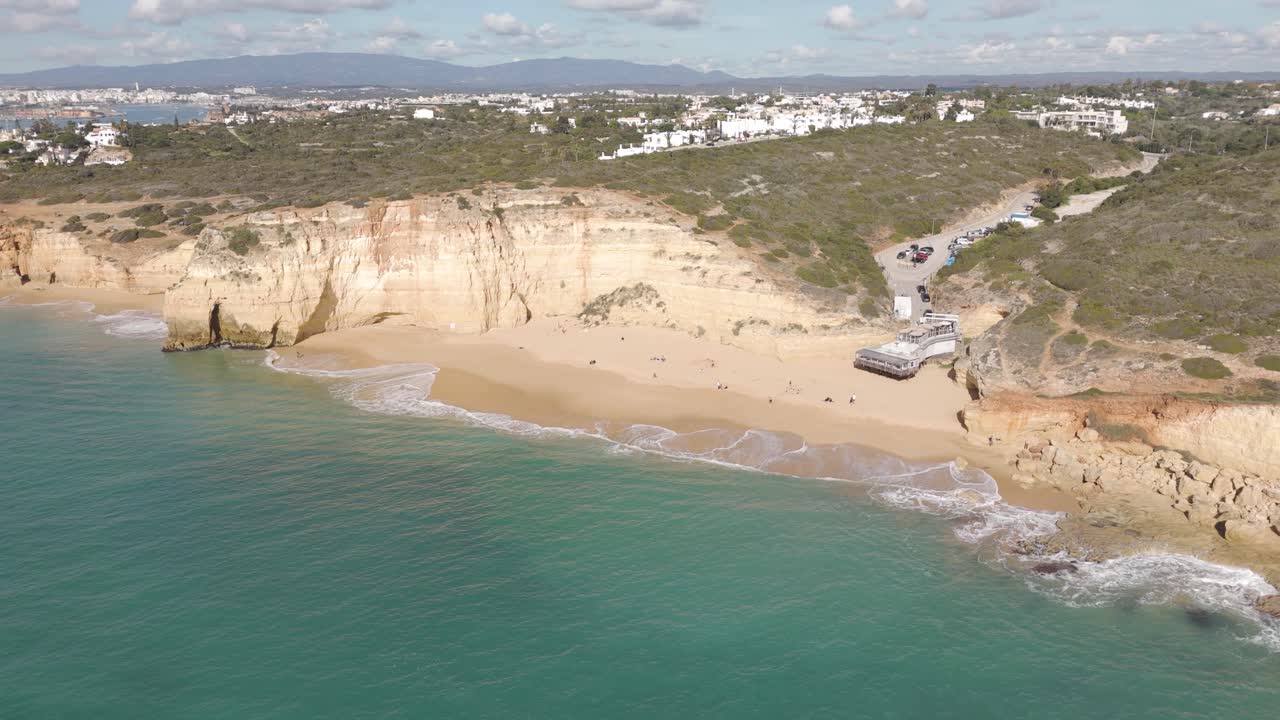Ripresa aerea con drone che sorvola Praia dos Caneiros, catturando la costa panoramica e le vedute sulla spiaggia lungo l'Algarve, in Portogallo
