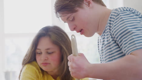 young downs syndrome couple mixing ingredients for cake recipe they are baking in kitchen at home