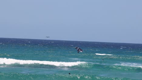 kite surfer glides across waves in sunny weather.