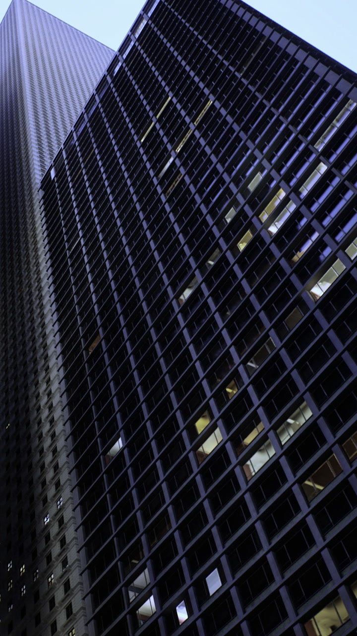 View of a tall building at night with glass windows and dark sky