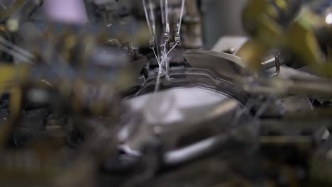close-up cámara lenta de hilo a la producción de calcetines - partes de la máquina con hilos, el proceso de producción en una fábrica de ropa, proceso automatizado, fabricación de ropa