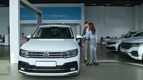 customer viewing a white suv in a car showroom