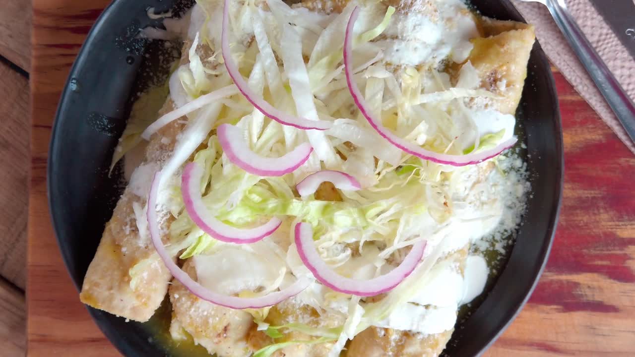 Traditional Mexican enchiladas enmoladas topped with lettuce and onions