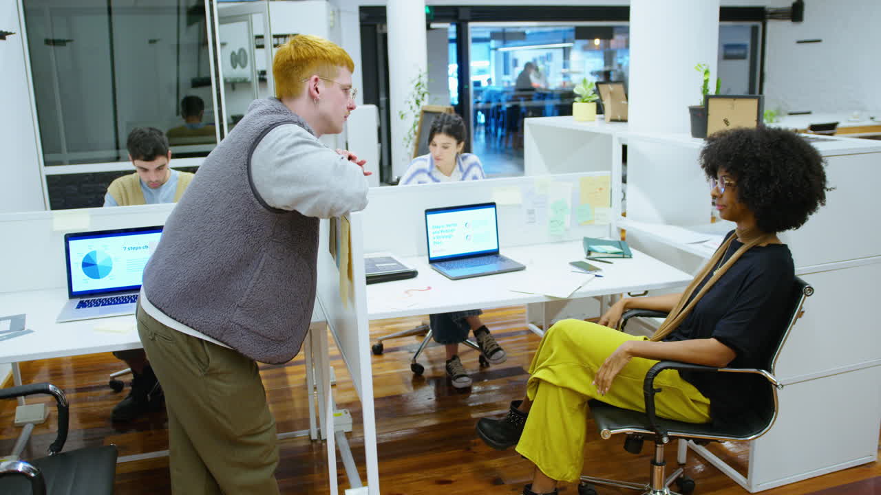Gen Z Coworkers Chatting Over Cubicle Wall in the Office