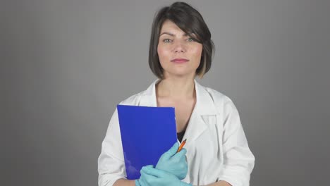 una joven enfermera amigable con una carpeta aislada sobre un fondo gris. concepto de atención médica. filmado en 4k.