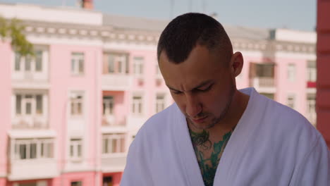 thoughtful man in bathrobe smokes cigarette on terrace