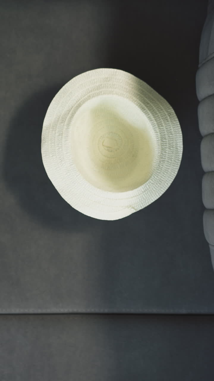 niño pequeño activo lanza sombrero de paja en el sofá suave cerca de la maleta. accesorio elegante para las vacaciones de verano en la habitación del hotel vista cercana superior