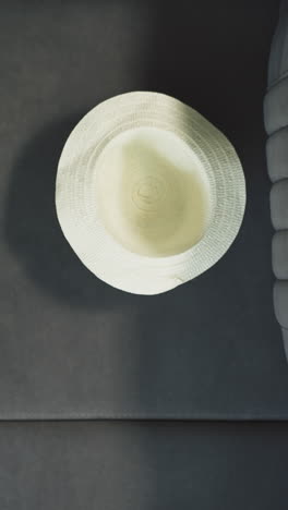 active toddler boy throws straw hat on soft couch near suitcase. stylish accessory for summer vacation in hotel room upper close view