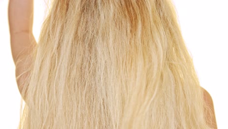 a blond woman touching her long hair to make some relaxing movement before combing it