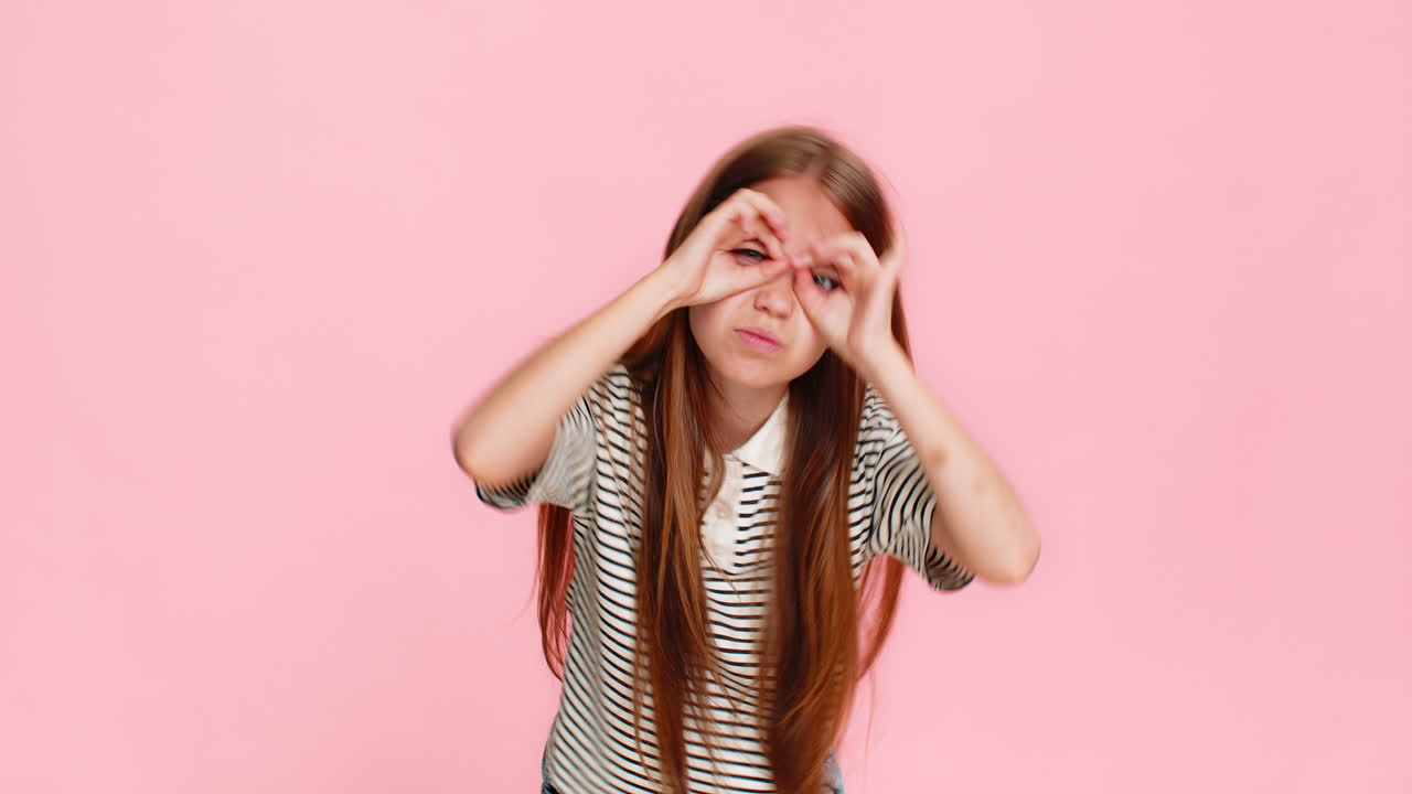 Child girl kid playfully forms glasses with fingers pretending to be smart see everything clearly