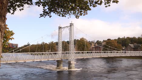 puente peatonal que cruza el río rushing en inverness, escocia en las tierras altas