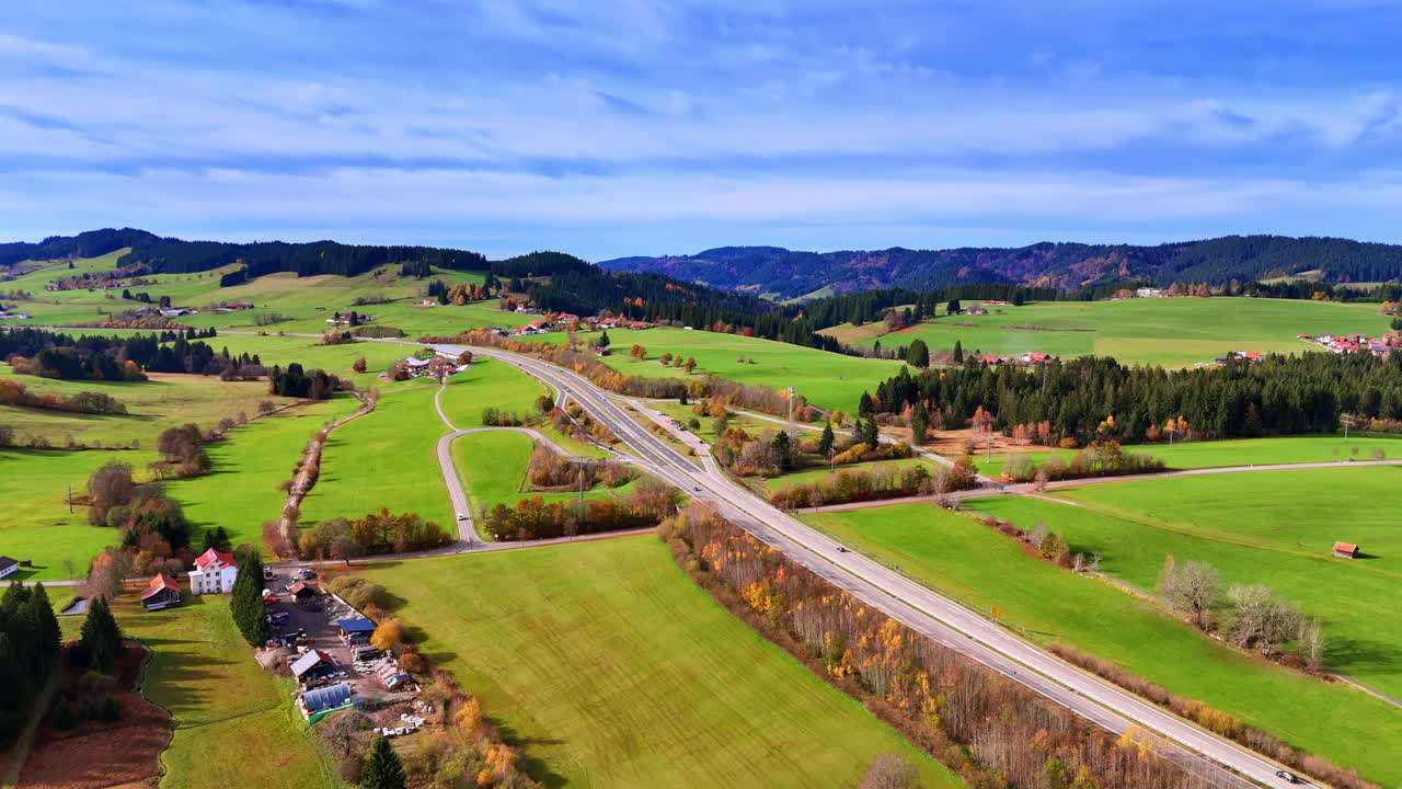 Vista aerea di strada tortuosa e autostrada in Germania. Vista dall'alto dell'infrastruttura stradale tra campi agricoli verdi, foreste e case residenziali.