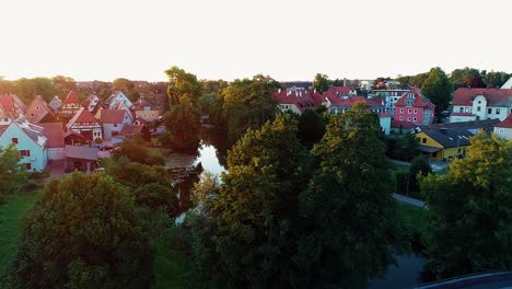 aerial view drone flies over the trees in the park meadows bridge the river the sun the sun's rays at sunset