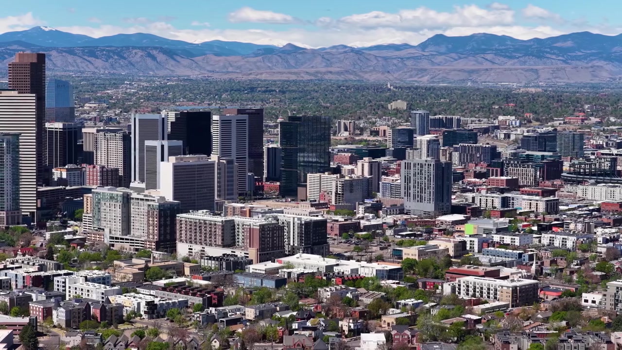 Luftfoto fra drone af tagene i Ballpark-kvarteret i Denver med byens tårne og bjerge i baggrunden.