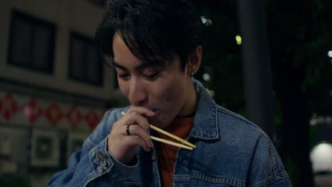 young man eating dinner outdoors at night
