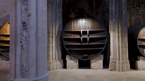 aerial dolly shot along large wine caskets stored within a french abbey