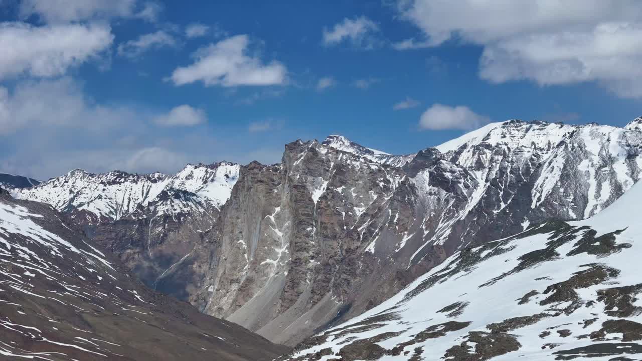 Aerial drone shot capturing the remote, snowy terrain of Shinkula Pass with contrasting rocky outcrops.