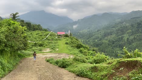 Vista-Trasera-De-Una-Joven-India-Feliz-Caminando-Por-Caminos-De-Montaña-Y-Visitando-La-Tumba-Tradicional-De-Budista-O-Gompa-En-La-Llanura-Cerca-De-La-Lava,-India-En-La-Cima-De-La-Colina