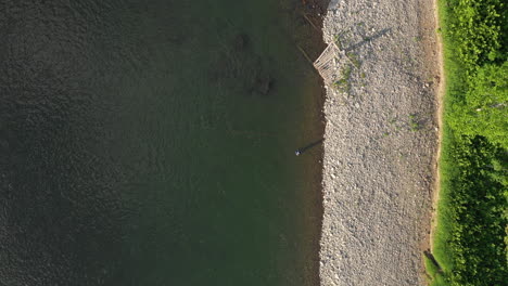Aerial-Drone-Footage-of-Fly-Fisherman-Spey-Casting-by-the-river-bank-at-Restigouches,-New-Brunswick,-Canada
