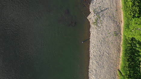 aerial drone footage of fly fisherman spey casting by the river bank at restigouches, new brunswick, canada