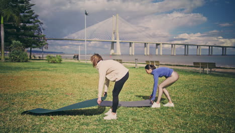 yoga girls putting carpets grass. athletes having pilates training sport routine