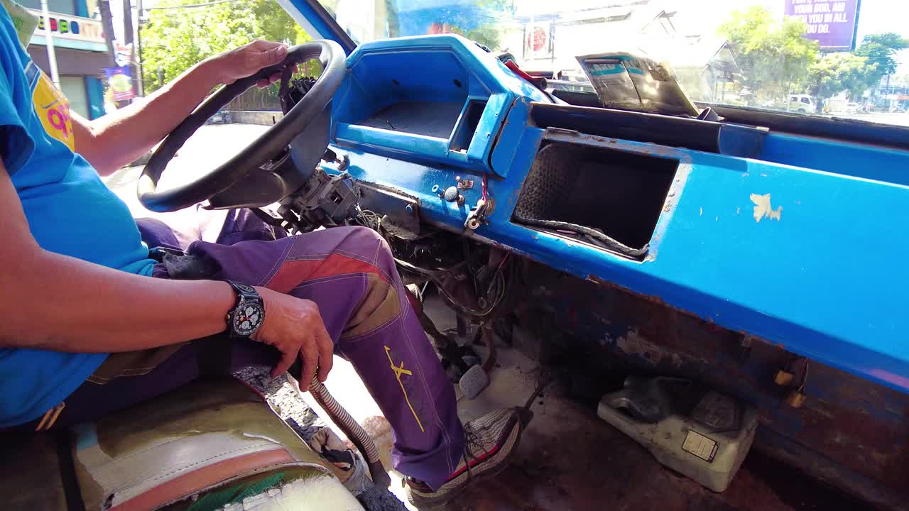 A driver on a Jeepney for public transportation. They are known for their crowded seating and kitsch decorations, which have become a widespread symbol of Philippine culture and art.