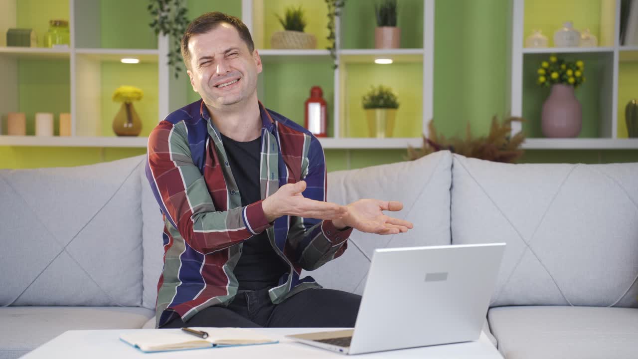 The man who gets emotional and starts to cry at the sight he sees on his laptop screen and looks at the camera.