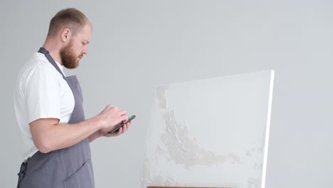 the artist applies a plaster base on a white canvas - the artist applies a plaster base on a white canvas. the artist works in his modern studio, modern abstract art