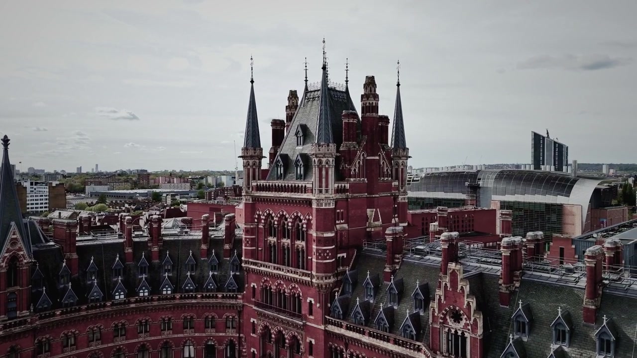 Ripresa panoramica con drone della stazione di St Pancras a Londra, che mostra la sua grandiosa facciata vittoriana, l'iconica torre dell'orologio e il paesaggio urbano circostante. Perfetto per viaggi, architettura e riprese urbane