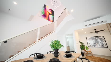sala de estar y comedor modernos con interior con escaleras, candelabro colgante y obras de arte coloridas