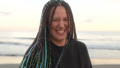 mujer con trenzas se ríe mirando la cámara en la playa