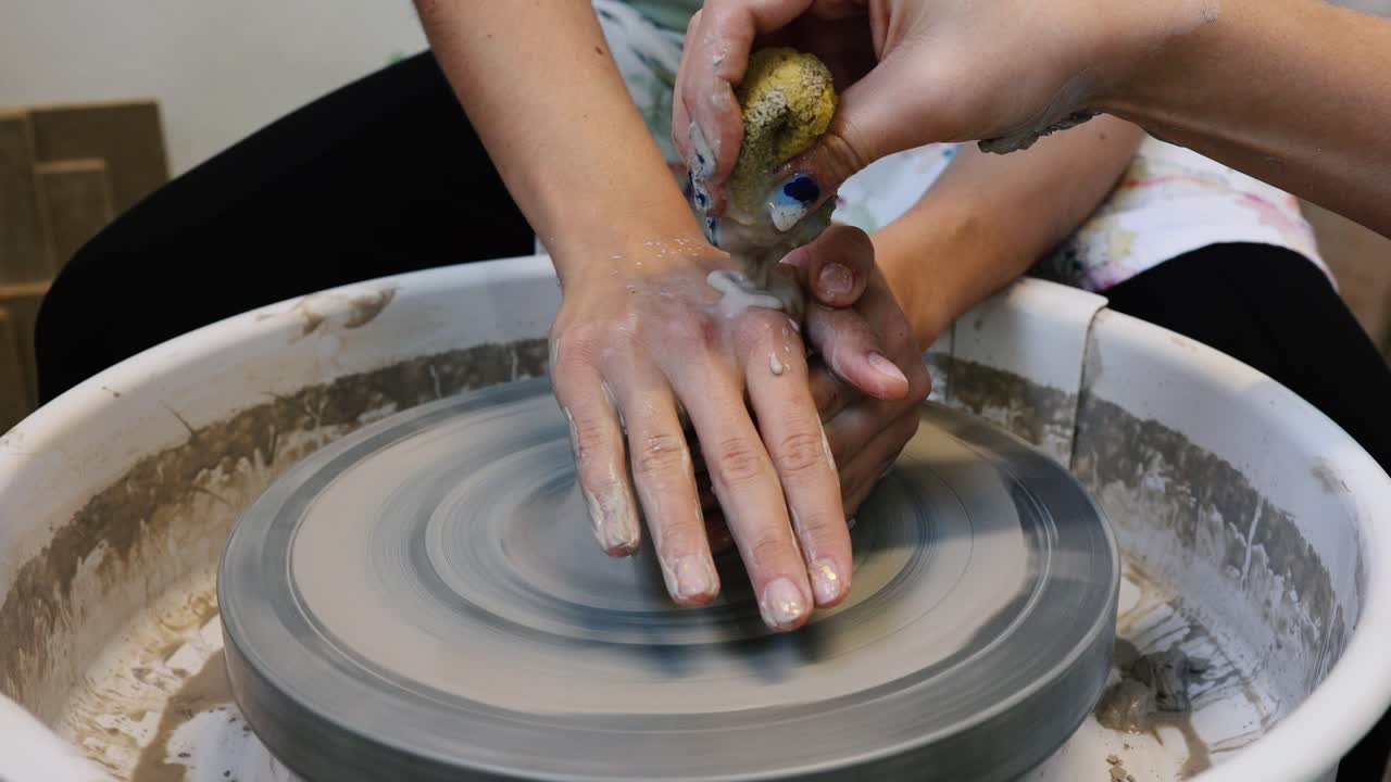 Young woman artist making clay bowl on pottery wheel