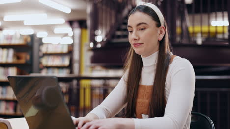 una mujer joven estudiando en una biblioteca.