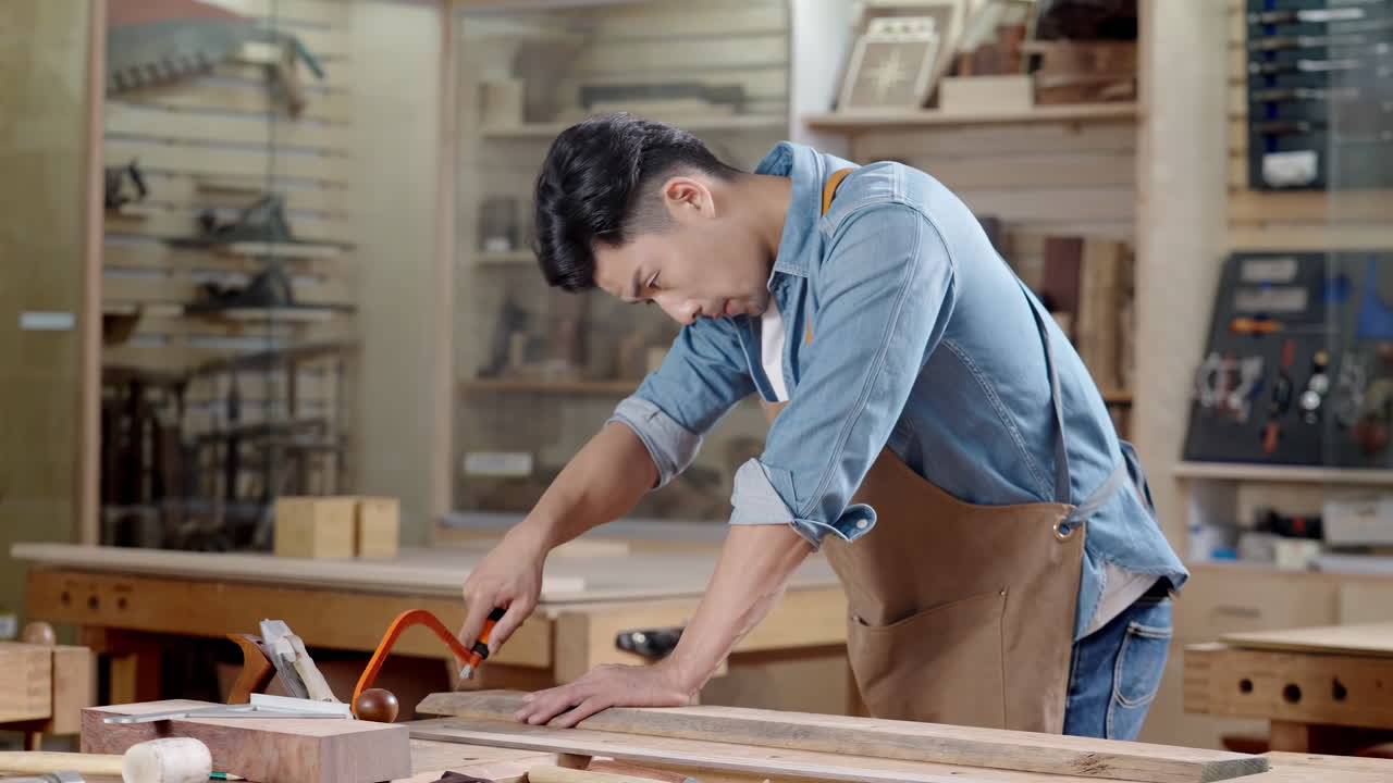 Eco friendly woodworker's shop, carpenters handmade craftsman uses a hand saw to carefully cut through a thick wooden beam during home renovation, he carefully follows markings on the blueprint