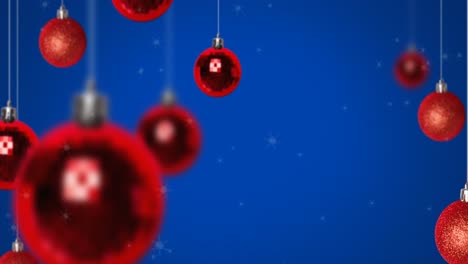 Animation-of-snow-falling-over-christmas-bauble-decorations-on-blue-background