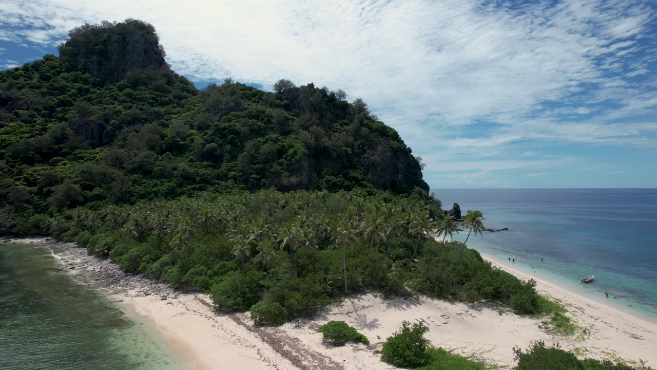 Tropical island with palm trees beach, help me sign, and boat anchored- aerial rotating