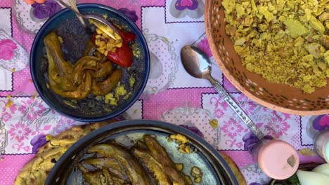 Pruebe-La-Comida-Tradicional-Sobre-Un-Mantel-Rosa-En-El-Campo-Rural-De-Irán-Khorasan,-Comida-Tradicional-De-Color-Púrpura-Hecha-Con-Tomate,-Berenjena-Y-Qurut,-El-Producto-Lácteo-Salado-Kashk,-A-Los-Turistas-Locales-Les-Encanta.